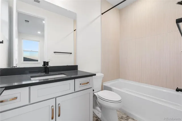a bathroom with a granite countertop sink toilet and a mirror