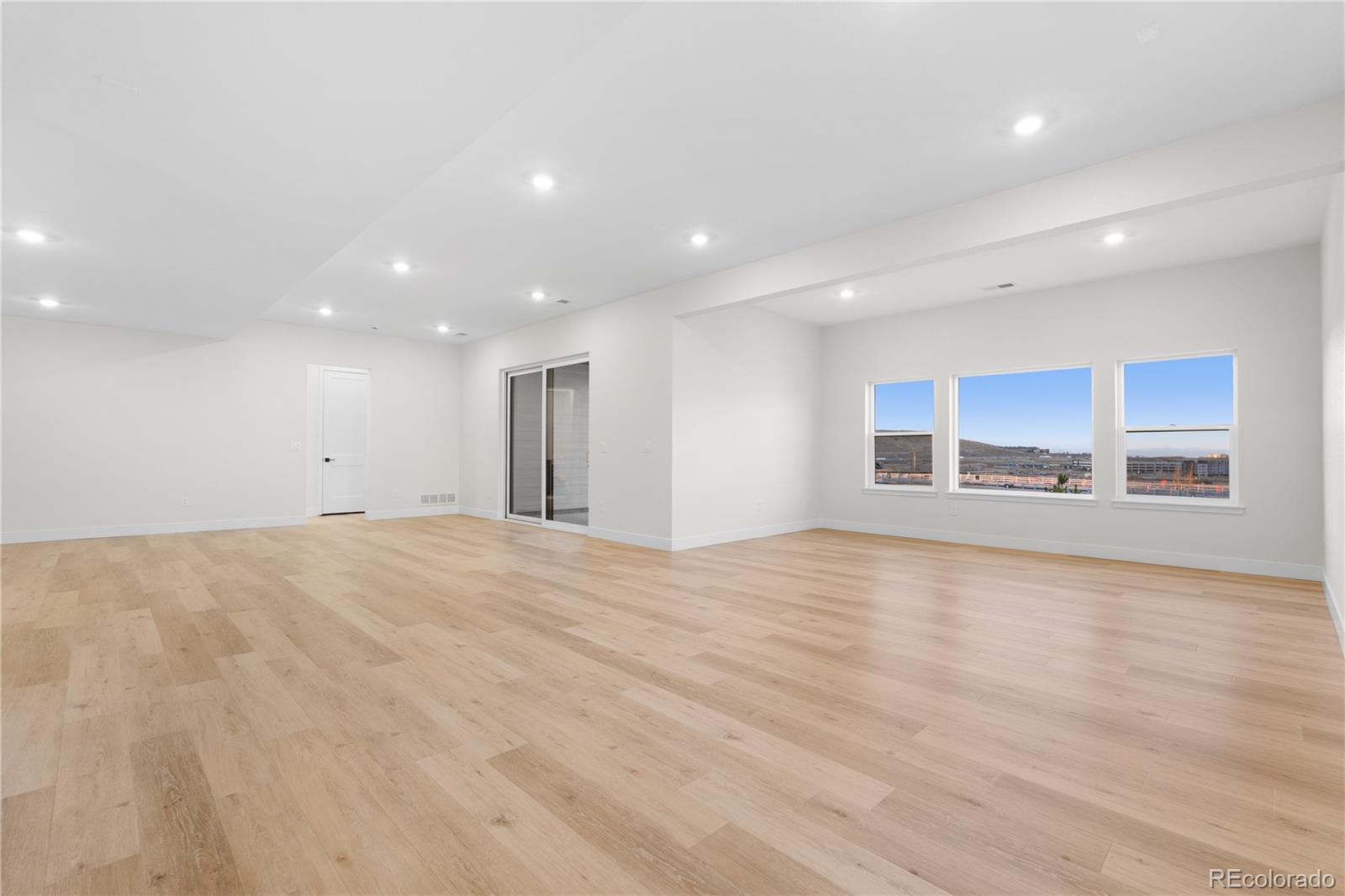 11283 Tenor Trail Lone Tree, CO 80134 - Photo 7 of 47 a view of an empty room with wooden floor and kitchen