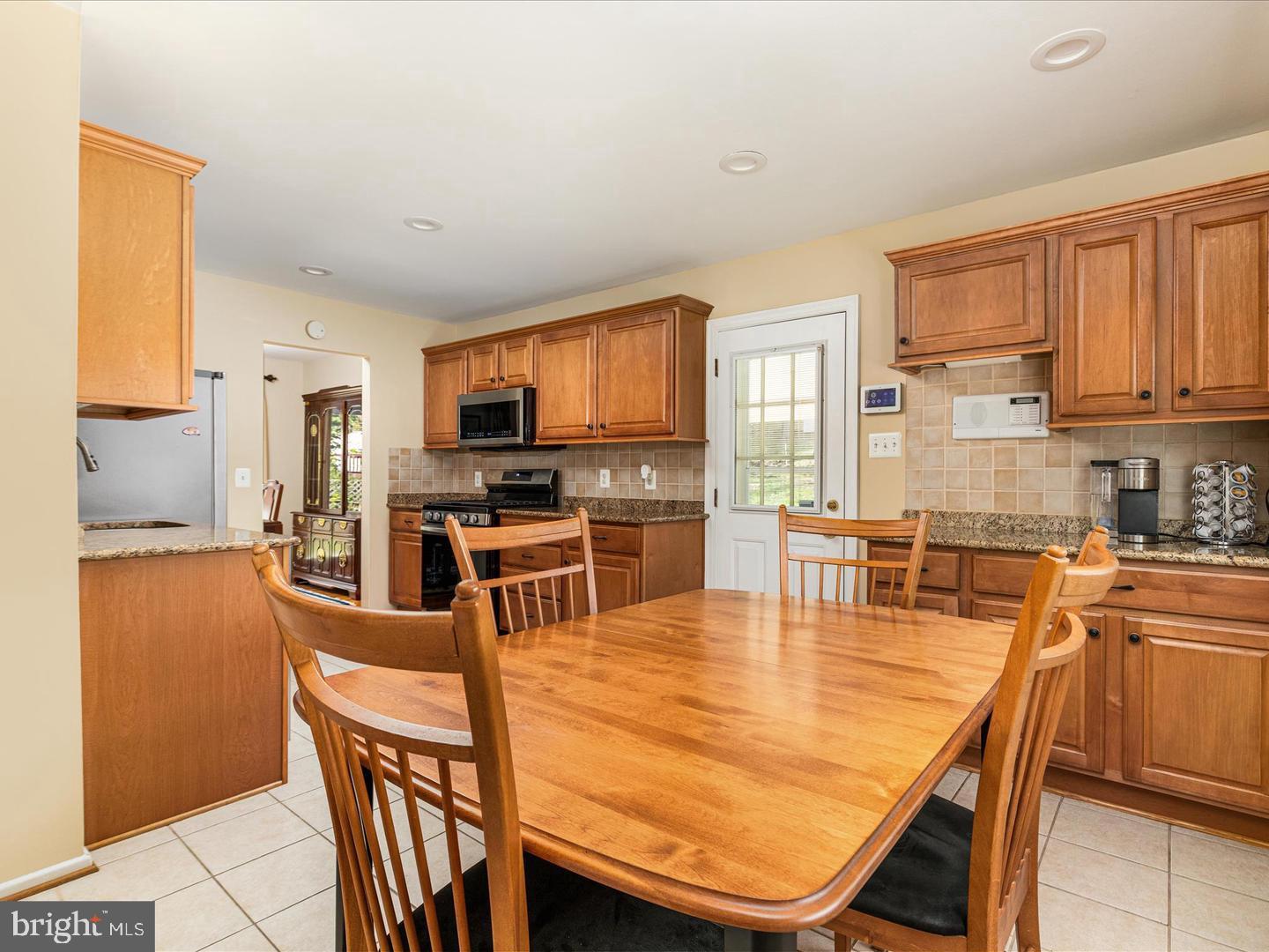 6434 Rives Court Springfield, VA 22150 - Photo 12 of 37 a kitchen with stainless steel appliances granite countertop a stove top oven a sink a dining table and chairs with wooden floor