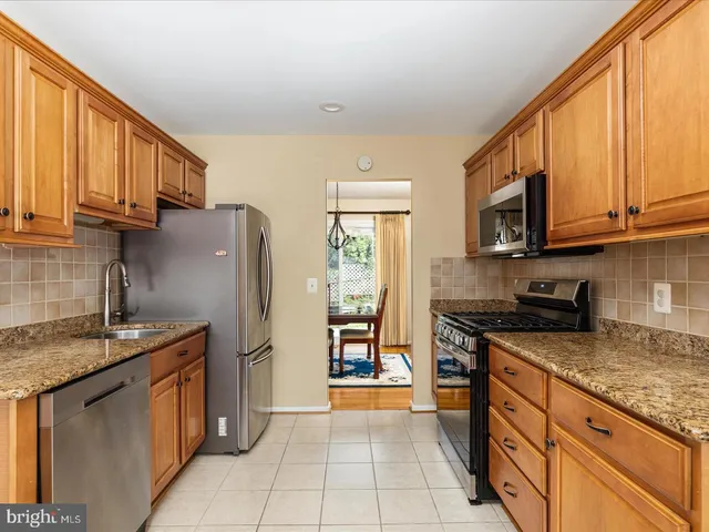 a kitchen with stainless steel appliances granite countertop a sink stove refrigerator and cabinets