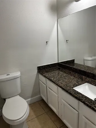 a bathroom with a granite countertop toilet sink and mirror