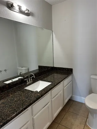 a bathroom with a granite countertop sink and a toilet