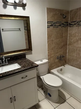 a bathroom with a granite countertop toilet sink and mirror