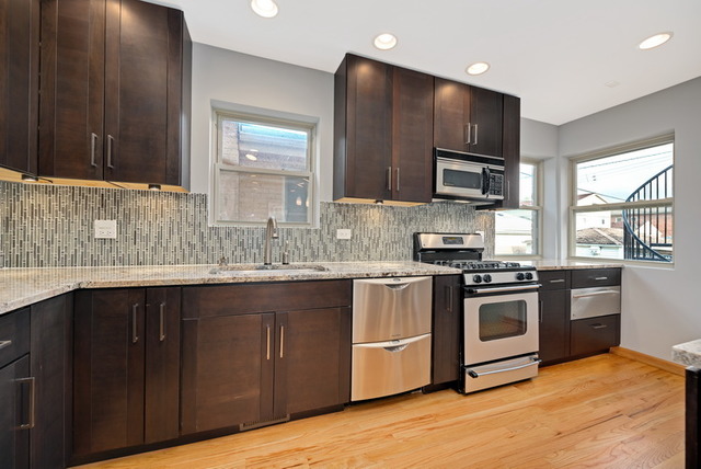 8013 West Irving Park Road Chicago, IL 60634 - Photo 11 of 25 a kitchen with stainless steel appliances granite countertop a stove a sink dishwasher and a microwave oven with cabinets