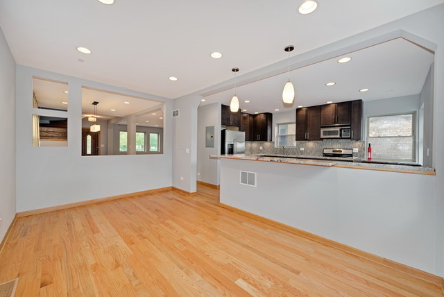 8013 West Irving Park Road Chicago, IL 60634 - Photo 7 of 25 a view of kitchen with stainless steel appliances kitchen island a sink dishwasher and a fireplace with wooden floor