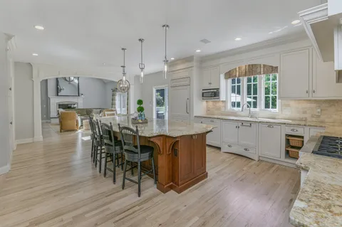 an open kitchen with wooden floor and stainless steel appliances