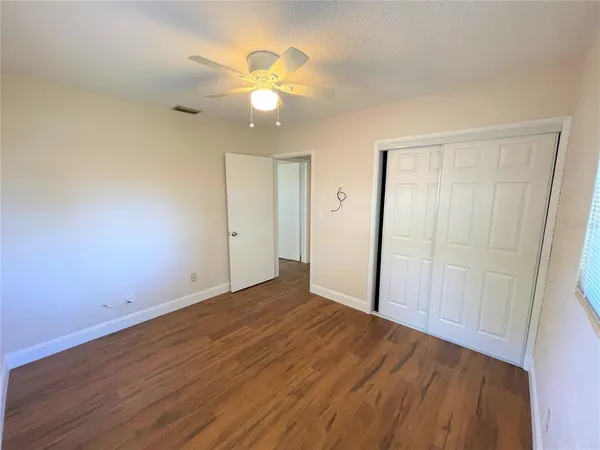 an empty room with wooden floor and fan