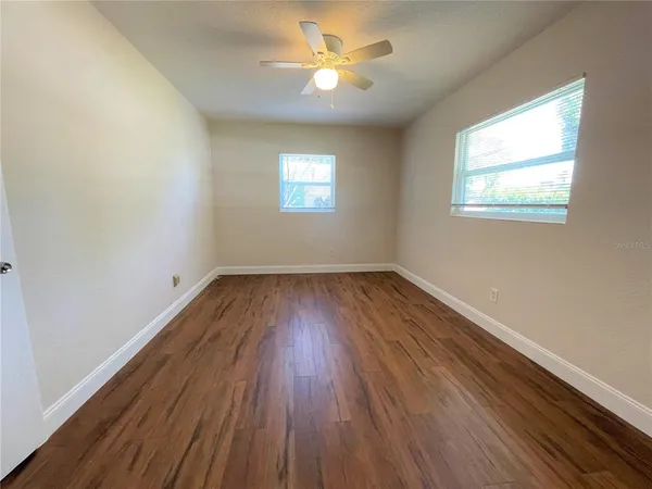 a view of empty room with wooden floor and fan