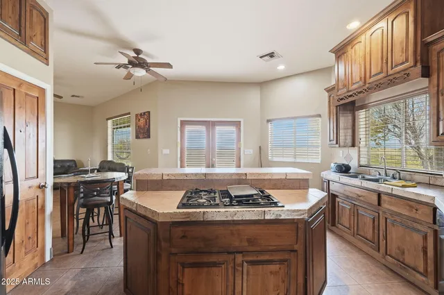 a kitchen with stainless steel appliances granite countertop a sink a stove a refrigerator cabinets and dining table