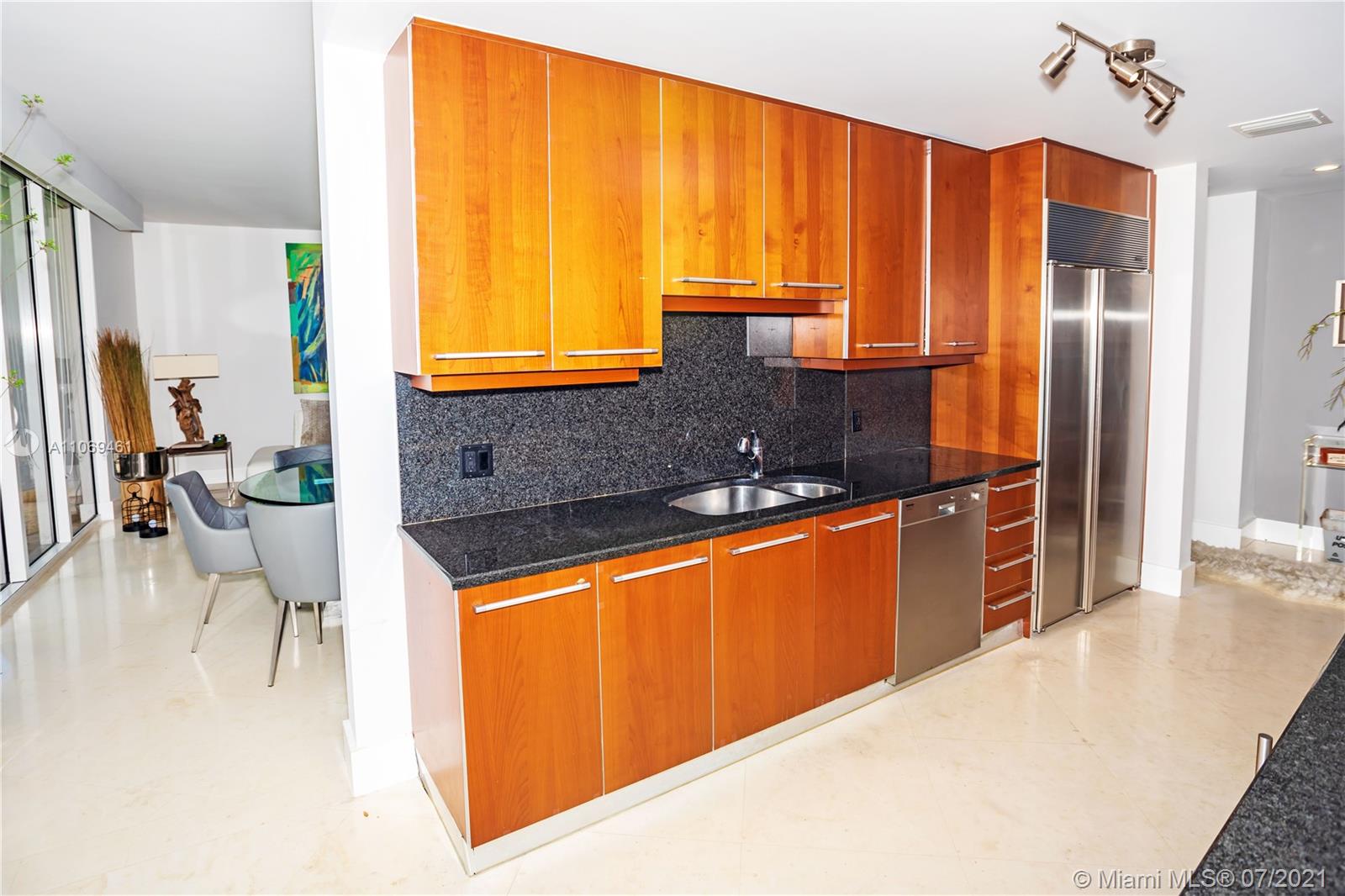 901 Brickell Key Boulevard, Unit 1406 Miami, FL 33131 - Photo 7 of 25 a kitchen with stainless steel appliances kitchen island granite countertop a sink refrigerator and cabinets