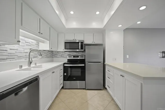 a kitchen with stainless steel appliances a sink a stove a refrigerator cabinets and a dining table