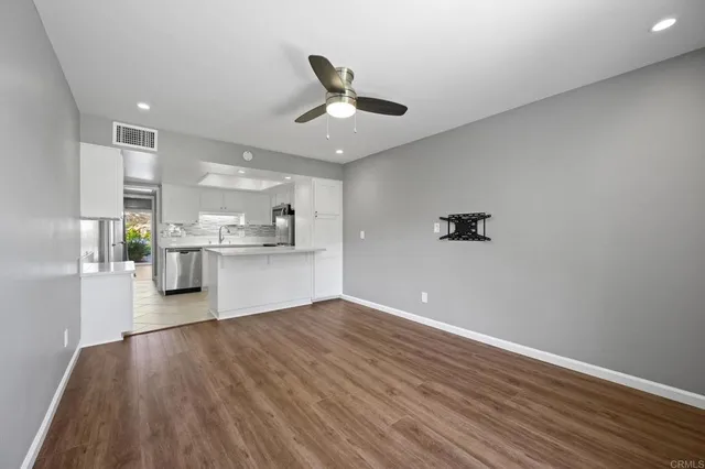 a view of kitchen and empty room with wooden floor