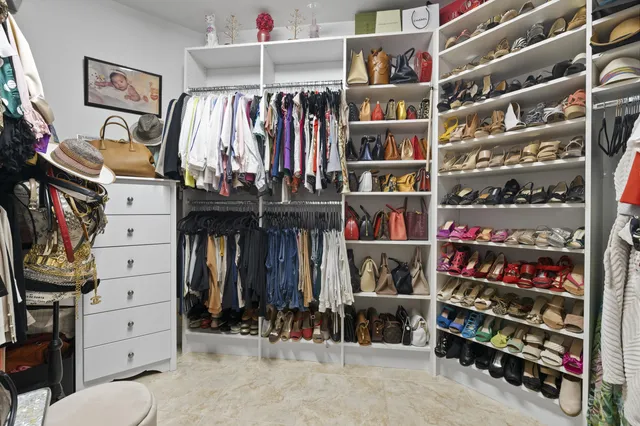 a view of walk in closet with clothes and shoes