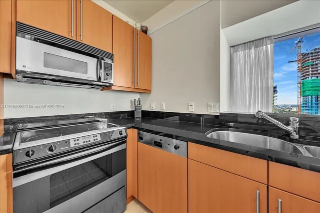 a kitchen with stainless steel appliances granite countertop a stove a sink and a microwave