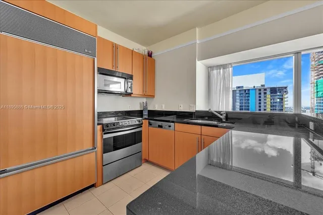 a kitchen with stainless steel appliances kitchen island granite countertop a table chairs and a refrigerator
