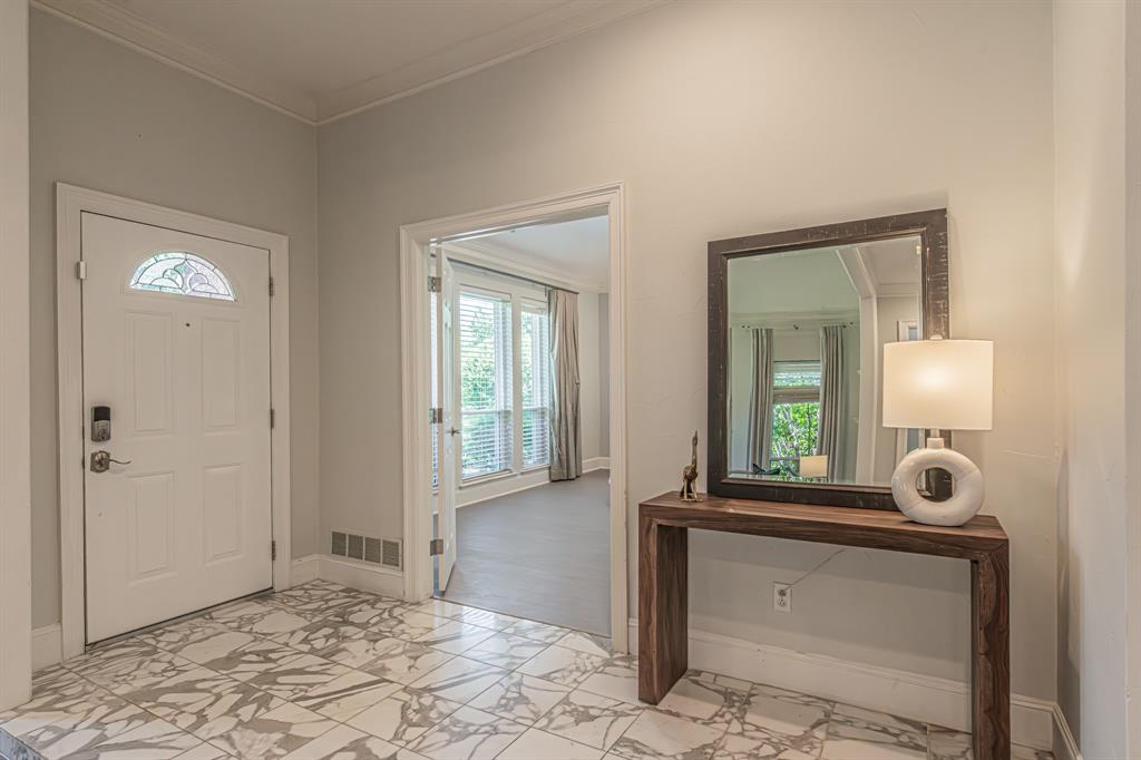 300 Sundance Circle Irving, TX 75063 - Photo 9 of 39 Foyer featuring marble-look tile flooring, crown molding, a white paneled entry door with decorative glass, and a wide cased opening to an interior room with large windows