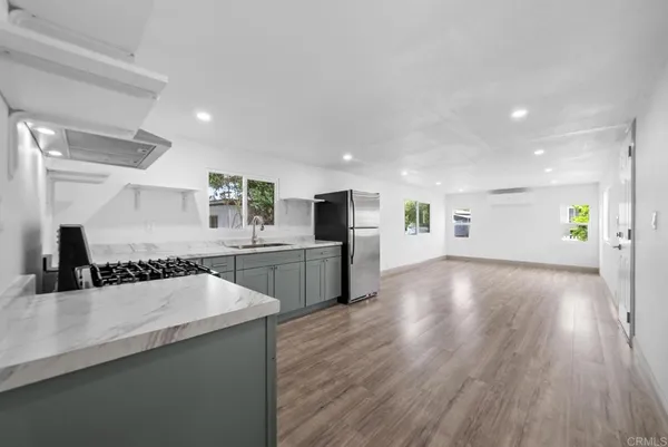 a large white kitchen with a lot of counter space and wooden floor