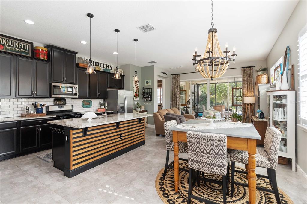 2463 Datura Loop St. Cloud, FL 34772 - Photo 13 of 57 a kitchen with stainless steel appliances kitchen island granite countertop a stove top oven a sink dishwasher a dining table and chairs with wooden floor