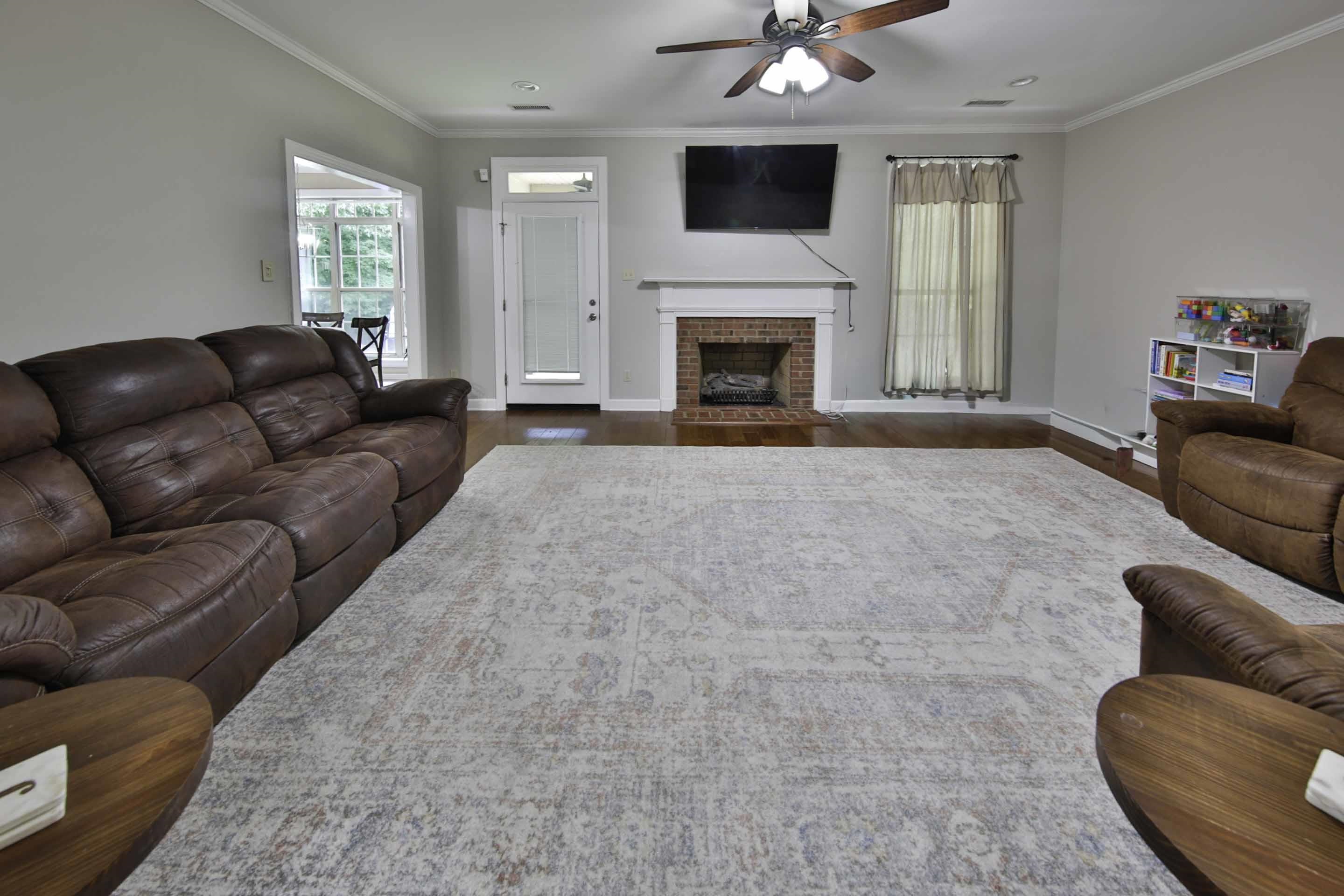 104 Miller Road Covington, TN 38019 - Photo 17 of 25 Spacious room featuring wood-finish flooring, a brick fireplace with a white mantel, and crown molding