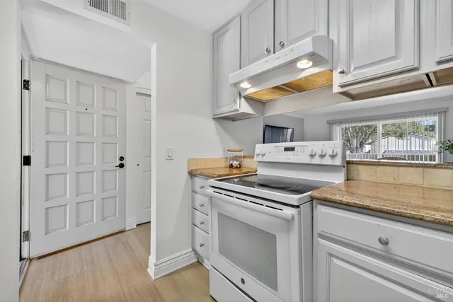 a kitchen with appliances cabinets and a wooden floor