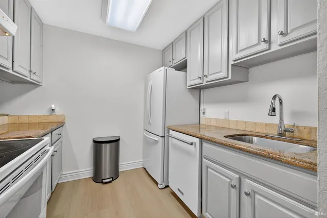 a kitchen with stainless steel appliances granite countertop a sink and a refrigerator