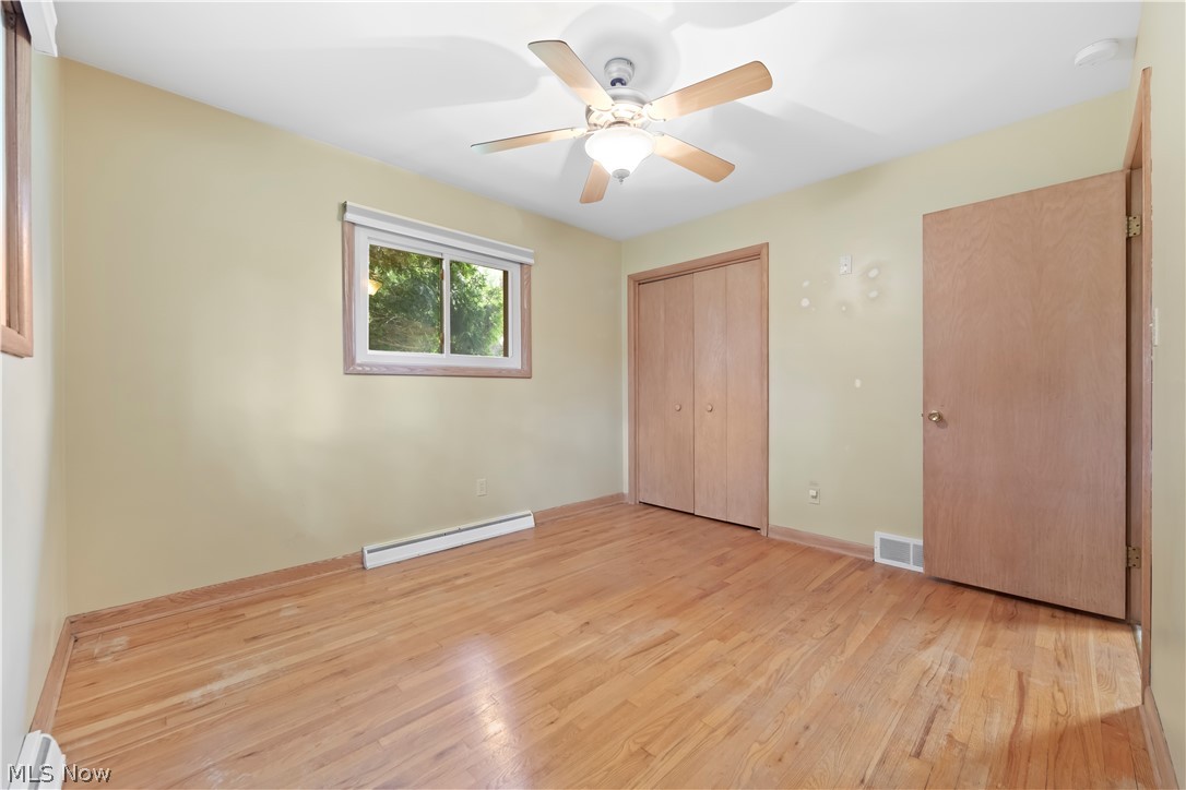 575 Overwood Road Akron, OH 44313 - Photo 26 of 45 Unfurnished bedroom featuring ceiling fan, a baseboard radiator, and light hardwood / wood-style flooring