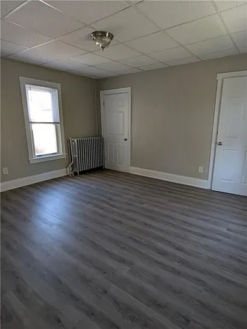 an empty room with wooden floor cabinet and windows