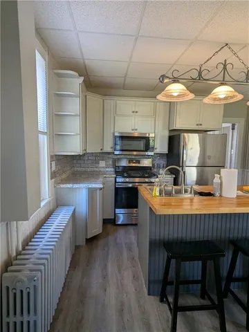 a kitchen with stainless steel appliances granite countertop a table chairs refrigerator and sink