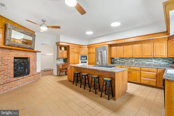 a large kitchen with stainless steel appliances granite countertop a stove top oven a sink dishwasher and white cabinets with wooden floor