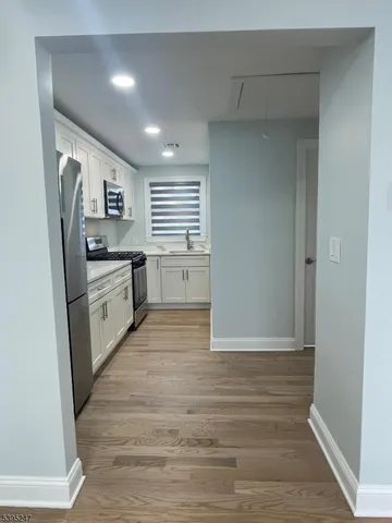 a large white kitchen with stainless steel appliances granite countertop a stove a sink and a refrigerator