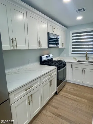 a kitchen with stainless steel appliances granite countertop a stove a sink and a microwave