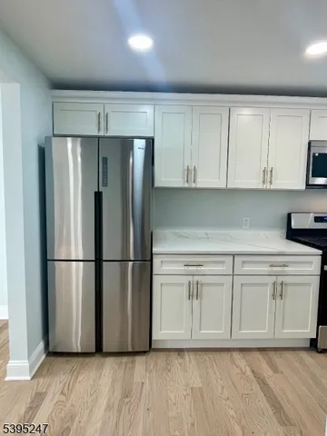 a kitchen with stainless steel appliances white cabinets white walls and a refrigerator