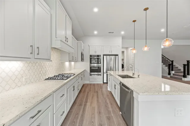 a large kitchen with white cabinets and stainless steel appliances