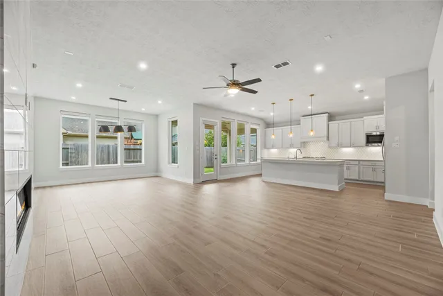 a view of an empty room with wooden floor and kitchen