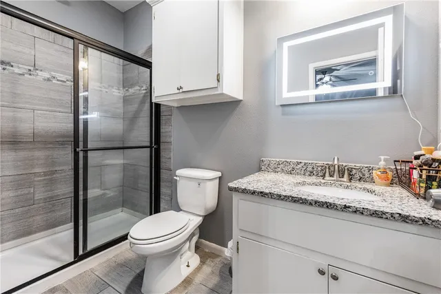 a bathroom with a granite countertop bathtub sink vanity mirror and toilet