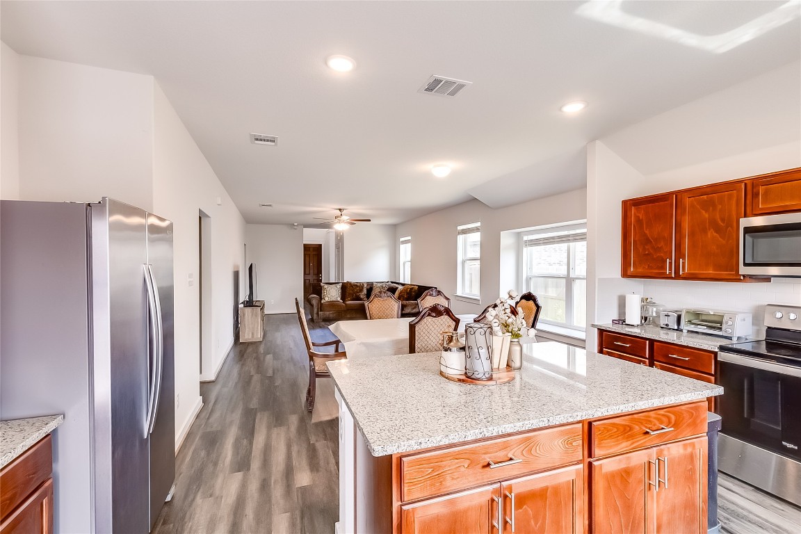 1104 Terrace View Georgetown, TX 78628 - Photo 36 of 36 a kitchen with stainless steel appliances kitchen island granite countertop a refrigerator a sink a stove and island with wooden floor