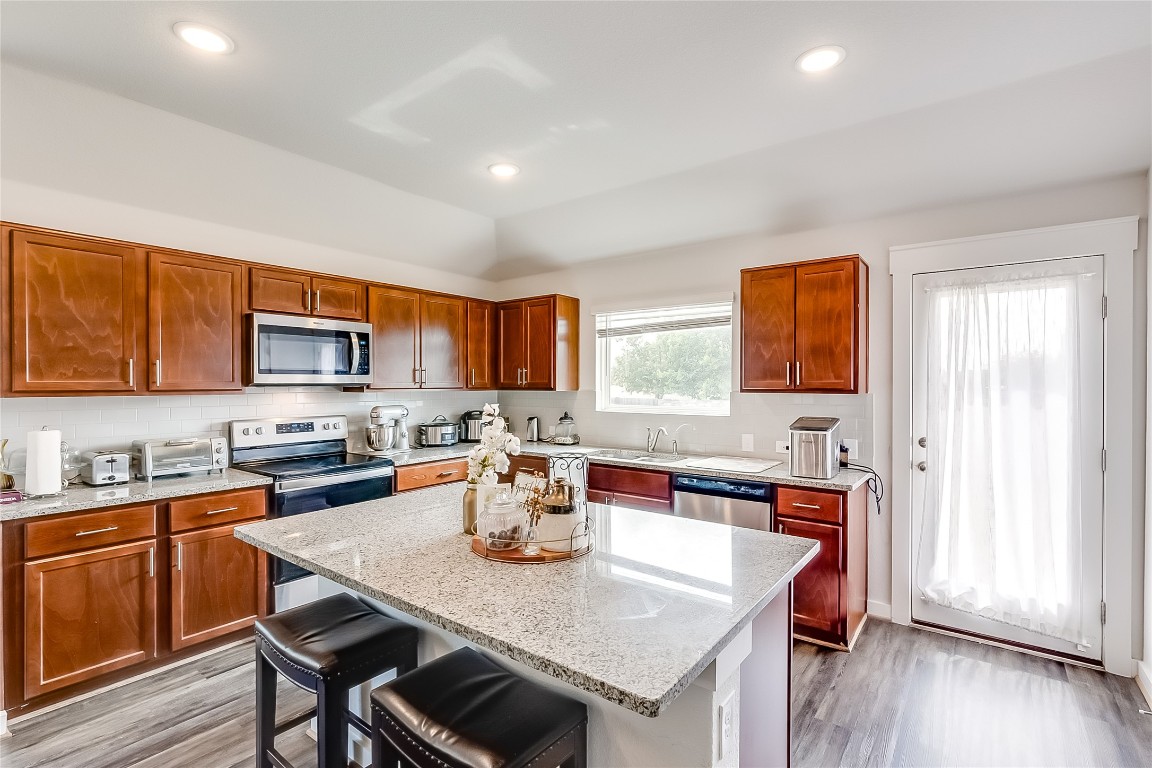 1104 Terrace View Georgetown, TX 78628 - Photo 9 of 36 a kitchen with a stove a sink dishwasher a dining table and chairs with wooden floor