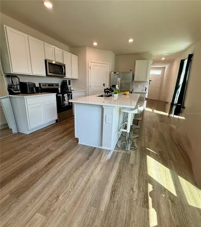 a kitchen with a sink a microwave a stove and white cabinets