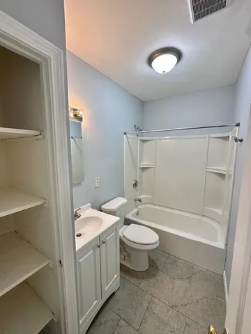 a bathroom with a granite countertop sink toilet mirror and bathtub