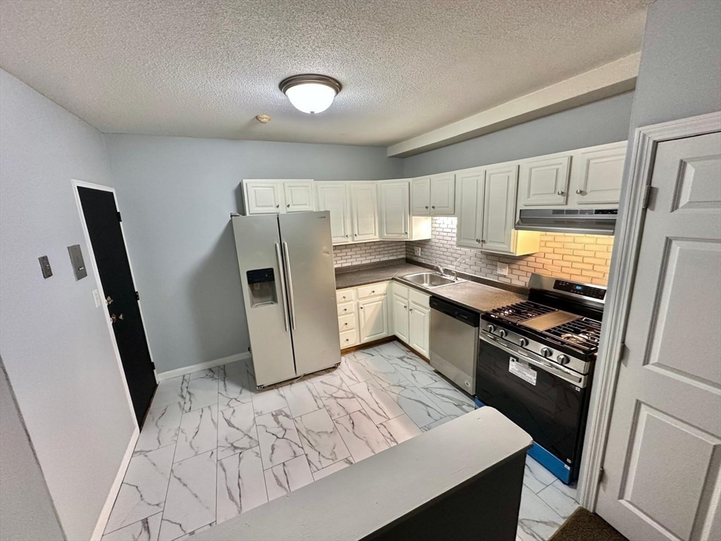 363 Hildreth Street, Unit 11 Lowell, MA 01850 - Photo 7 of 17 a kitchen with granite countertop a refrigerator stove and sink