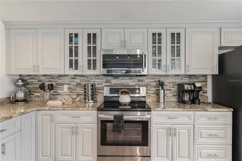 a kitchen with granite countertop white cabinets and stainless steel appliances