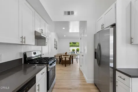 a kitchen with stainless steel appliances granite countertop a refrigerator a stove and a sink