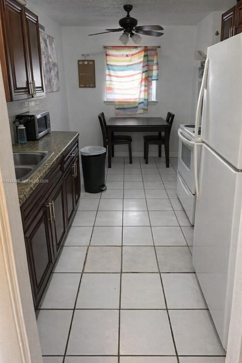 1489 West 34th Street Riviera Beach, FL 33404 - Photo 3 of 6 a kitchen with granite countertop a stove a sink and a refrigerator