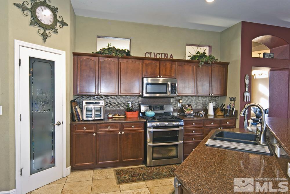 1795 Arrow Wood Court Reno, NV 89521 - Photo 11 of 40 a kitchen with stainless steel appliances granite countertop a stove top oven a sink dishwasher and a refrigerator with wooden floor