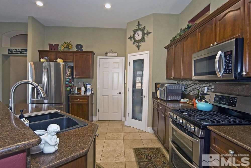 1795 Arrow Wood Court Reno, NV 89521 - Photo 13 of 40 a kitchen with stainless steel appliances granite countertop a stove refrigerator and a microwave