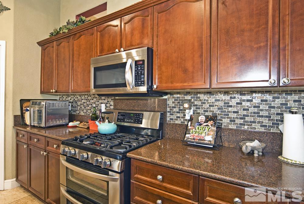 1795 Arrow Wood Court Reno, NV 89521 - Photo 14 of 40 a kitchen with granite countertop a stove top oven microwave and cabinets