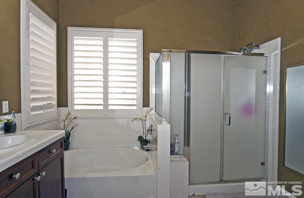 1795 Arrow Wood Court Reno, NV 89521 - Photo 23 of 40 a bathroom with a bathtub a shower a sink and a window