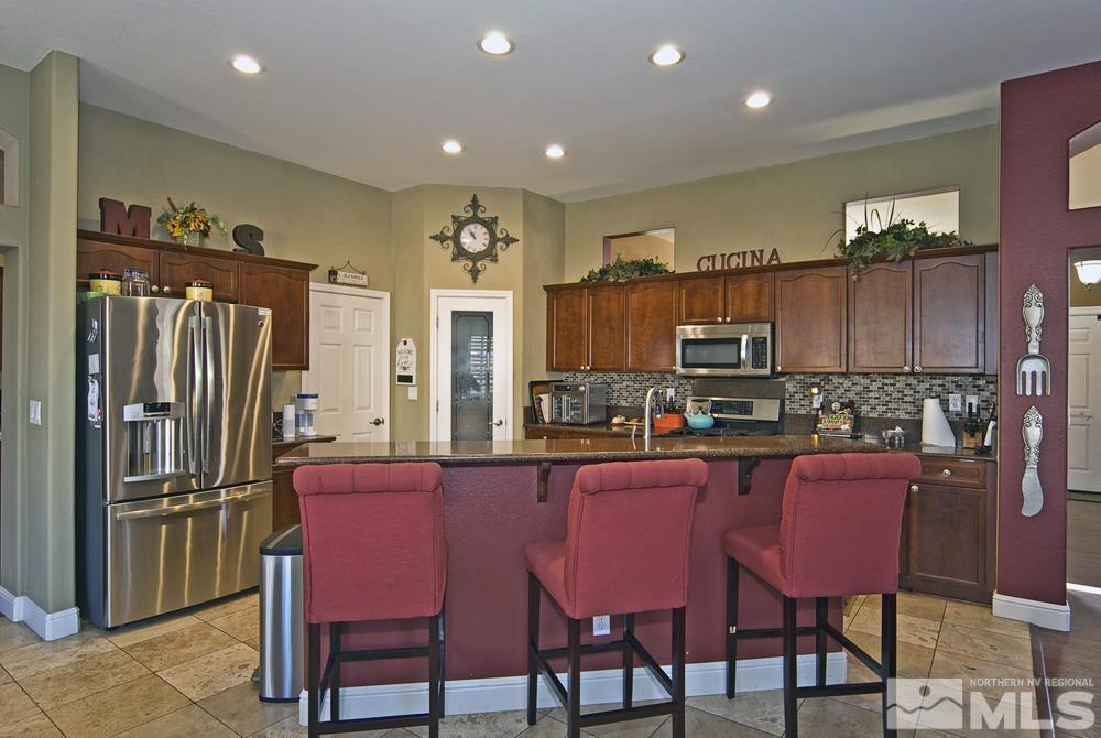 1795 Arrow Wood Court Reno, NV 89521 - Photo 10 of 40 a kitchen with granite countertop a dining table chairs cabinets and stainless steel appliances