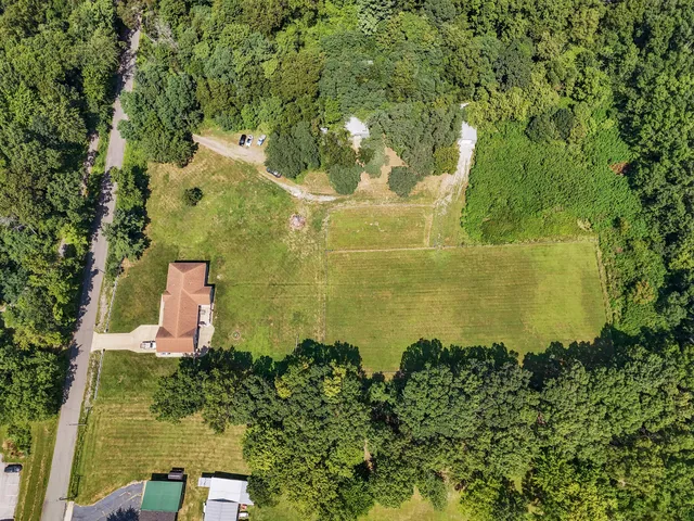 an aerial view of residential houses with outdoor space and trees all around