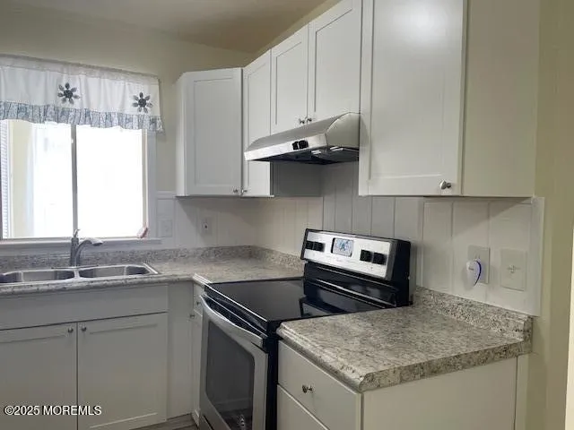 a kitchen with granite countertop a sink stove and cabinets